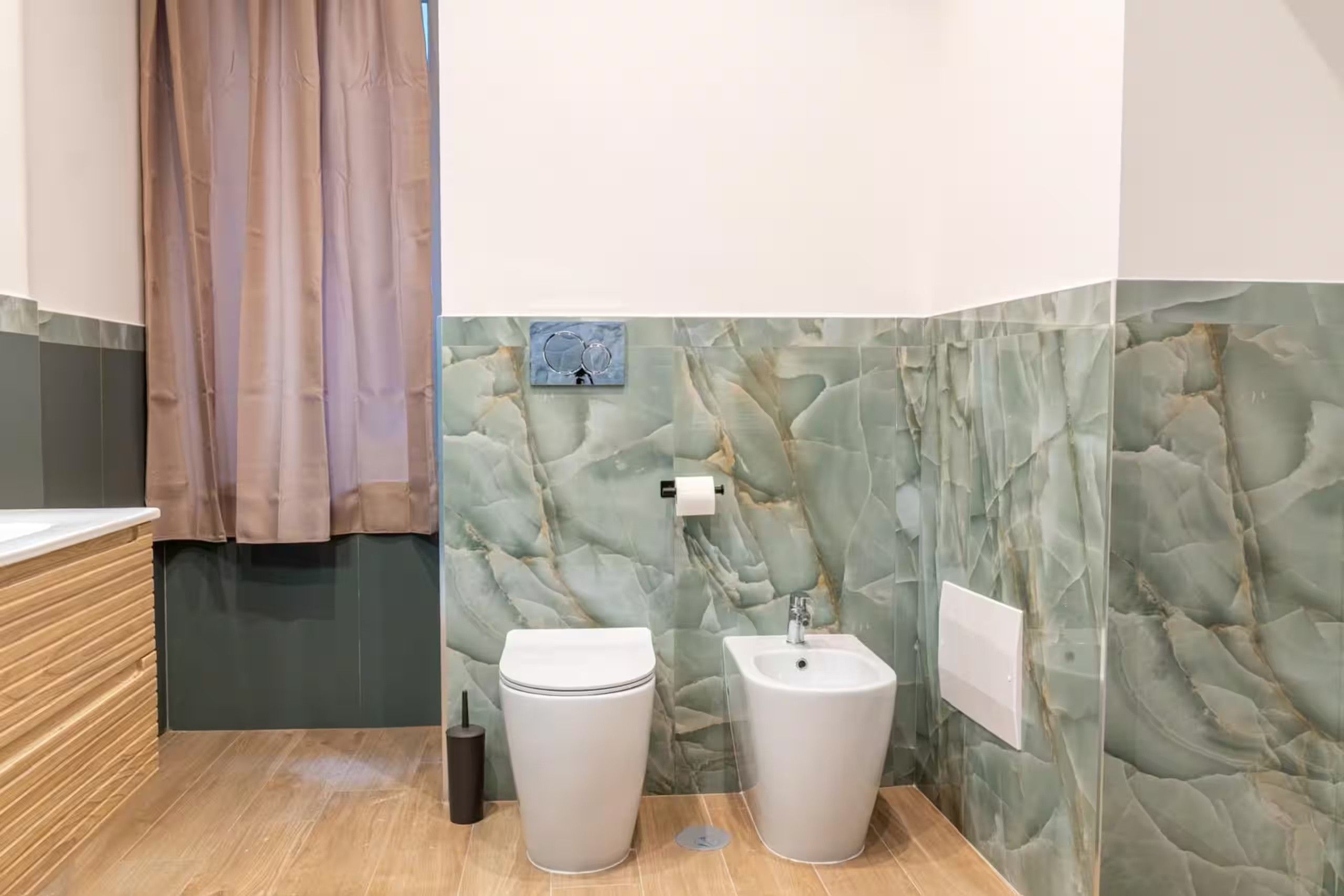 Ein Badezimmer mit Marmorwand, Toilette, Waschbecken und einer Duschkabine.