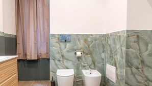 Ein Badezimmer mit Marmorwand, Toilette, Waschbecken und einer Duschkabine.