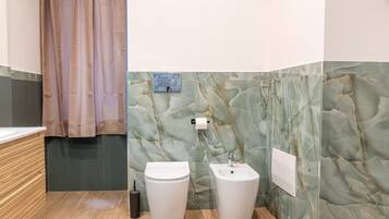 Ein Badezimmer mit Marmorwand, Toilette, Waschbecken und einer Duschkabine.