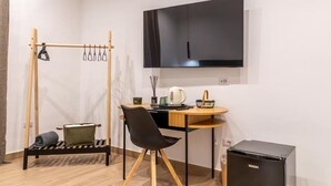 Une pièce de taille modeste comprenant un lit, un bureau, une chaise, un téléviseur et une petite kitchenette.