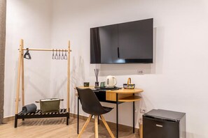 Pieni huone, jossa on sänky, työpöytä, tuoli, televisio ja pieni keittokomero.