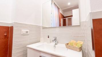 Un bagno con un lavandino bianco, uno specchio sopra e un porta asciugamani.
