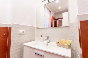 Un bagno con un lavandino bianco, uno specchio sopra e un porta asciugamani.
