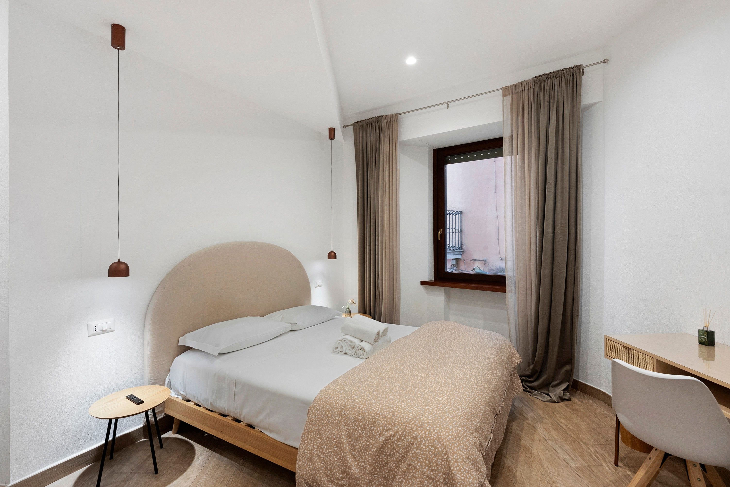 Una camera da letto con un letto, un comodino e una finestra con tende.
