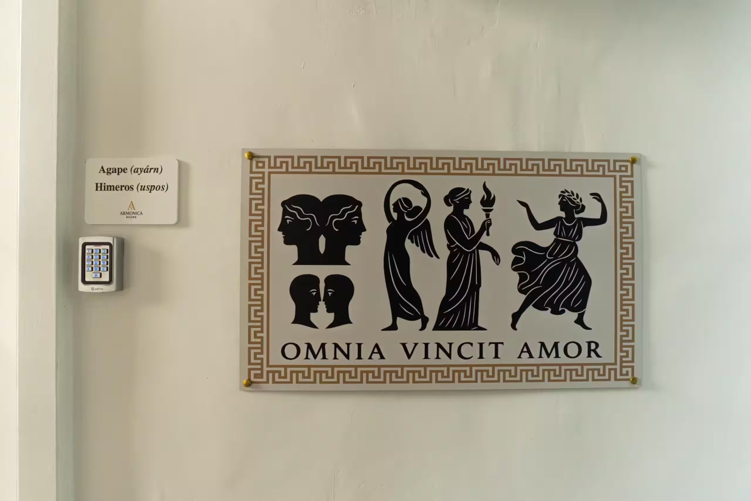 Un muro con un cartello decorativo raffigurante figure classiche e la frase 'OMNIA VINCIT AMOR'.