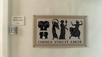 Un muro con un cartello decorativo raffigurante figure classiche e la frase 'OMNIA VINCIT AMOR'.