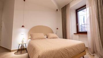 Una camera da letto con un letto, un comodino, una finestra con tende e vista sull'esterno.