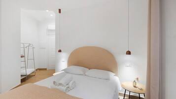 A modern bedroom with a large bed, bedside tables, a small round table, and a wardrobe.