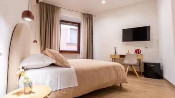 Una camera d'albergo con un letto, una scrivania, una sedia, un televisore e un tavolino con un vaso.