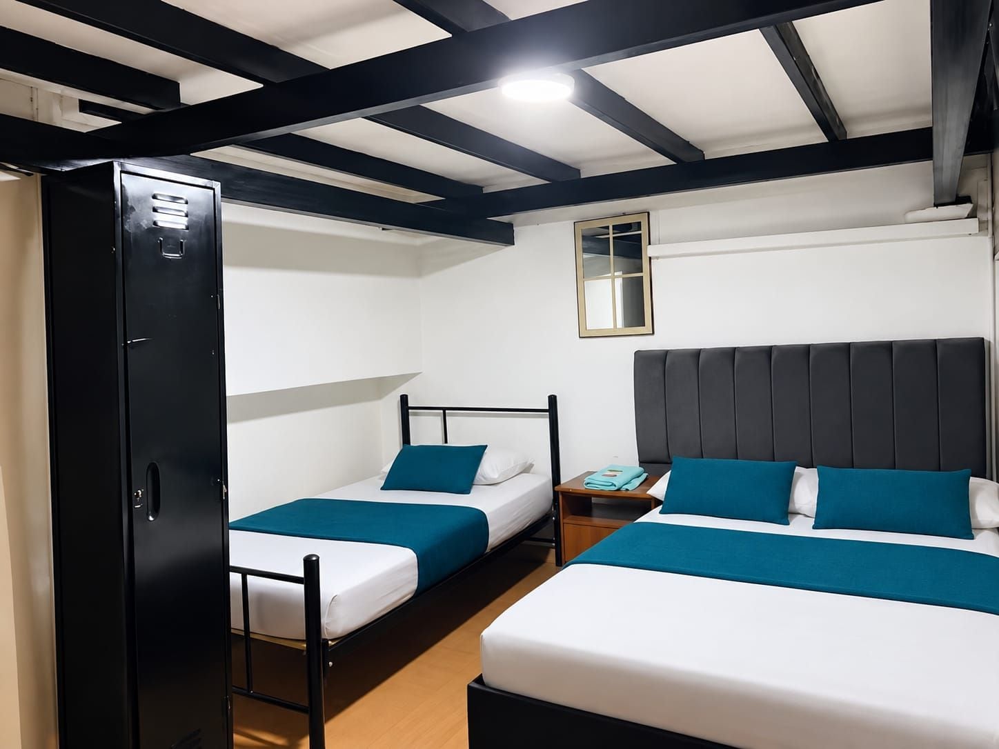 Une chambre avec deux lits, une armoire, une table de chevet et un miroir au mur.