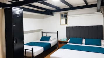 Quarto com duas camas, um guarda-roupa, uma mesa de cabeceira e um espelho na parede.