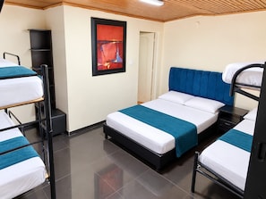 A hotel room with bunk beds, a bedside table, a framed artwork on the wall, and a door to the adjacent room. - Hotel Bogota Home (Bogotá)
