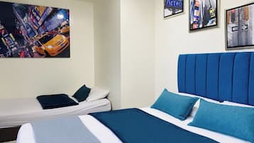 Habitación de hotel con una cama, una cama individual y dos cuadros en la pared.