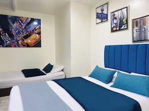 Habitación de hotel con una cama, una cama individual y dos cuadros en la pared.