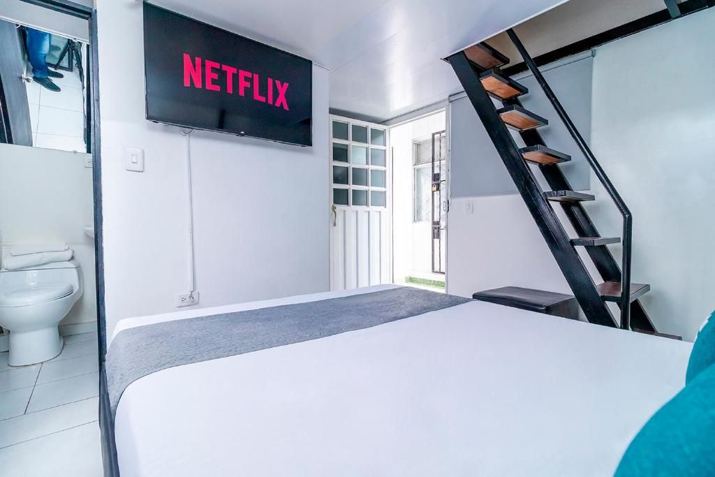 Quarto de hotel moderno com cama, TV na parede, escada e porta para o exterior.