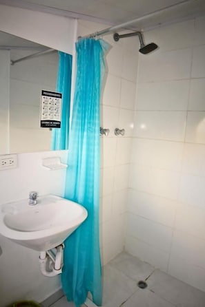 A bathroom with a white sink, a shower with a blue curtain, and a sign on the wall. - Hotel Bogota Home (Bogotá)