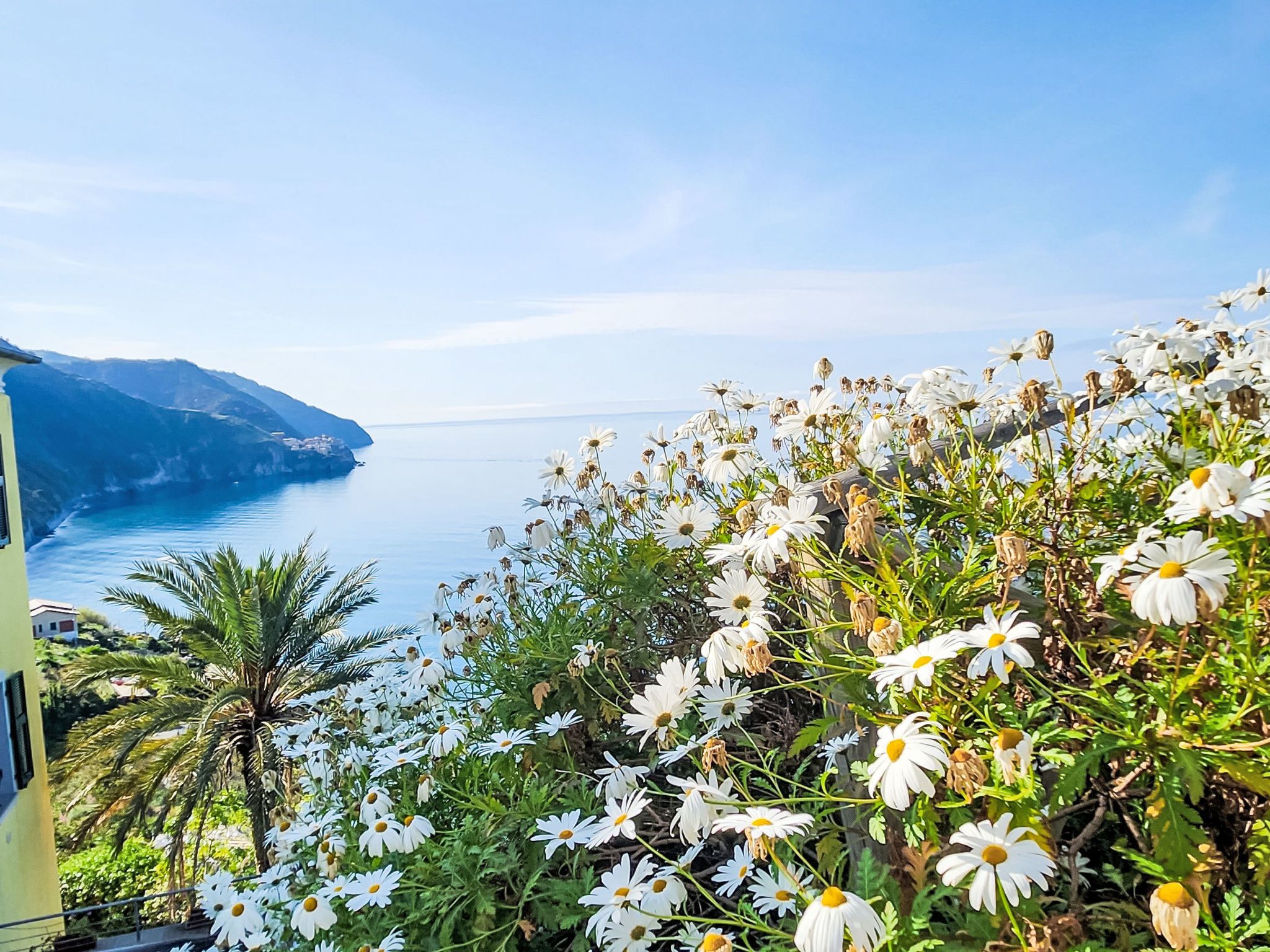 A coastal landscape with a view of the sea and a building on a hillside.
