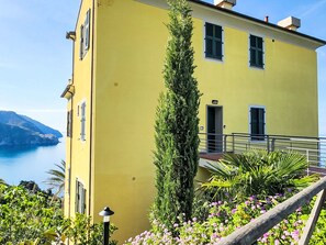 A yellow building with a balcony overlooking a body of water and mountains. - Marienkäfer by Interhome (Corniglia)