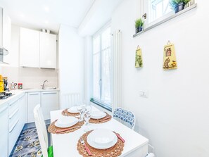A bright kitchen with white cabinets, a dining table set for four, and a window with a view. - Marienkäfer by Interhome (Corniglia)