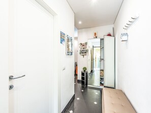 A hallway with a white door, a bench, a mirror, and a refrigerator. - Marienkäfer by Interhome (Corniglia)