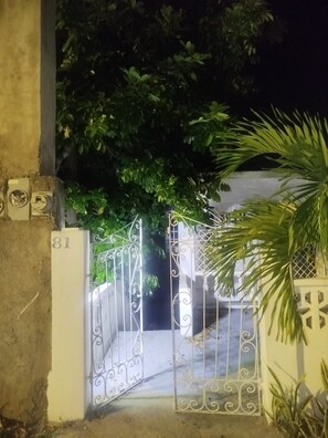 A gated entrance with a number '81' on the wall, surrounded by greenery.