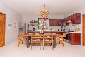 A modern kitchen with a central island, wooden chairs, a chandelier, and built-in wooden cabinets. - 8BR/4BA AC House in Playa Grande, 4 Min Walk to the Beach, Pool, Rancho, Parking (Playa Grande)