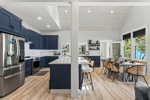 Une cuisine moderne avec des meubles de couleur bleu foncé, des appareils en acier inoxydable et un îlot central.