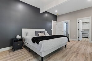 Un dormitorio moderno con una cama grande, una mesita de noche, un armario y un vestidor.