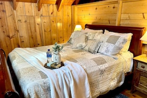 Una habitación con paneles de madera, una cama, una mesita de noche y una lámpara.