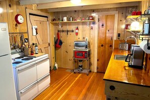 A kitchen with wooden walls, a white stove, a microwave, and a toaster. - Red Door Cottage. Close to town! Pet-friendly! (Twain Harte)