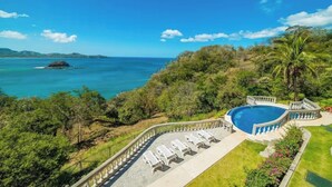 A pool with a curved edge, surrounded by a white fence and lounge chairs. - Romantic Getaway Studio Condo in Playa Flamingo.  Stunning ocean views w/2 pools (Playa Flamingo)