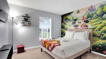 A bedroom with a bed, a desk, a red storage box, a window, and a wall mural.