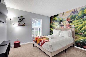 Un dormitorio con cama, un escritorio, una caja roja de almacenamiento, una ventana y un mural en la pared.