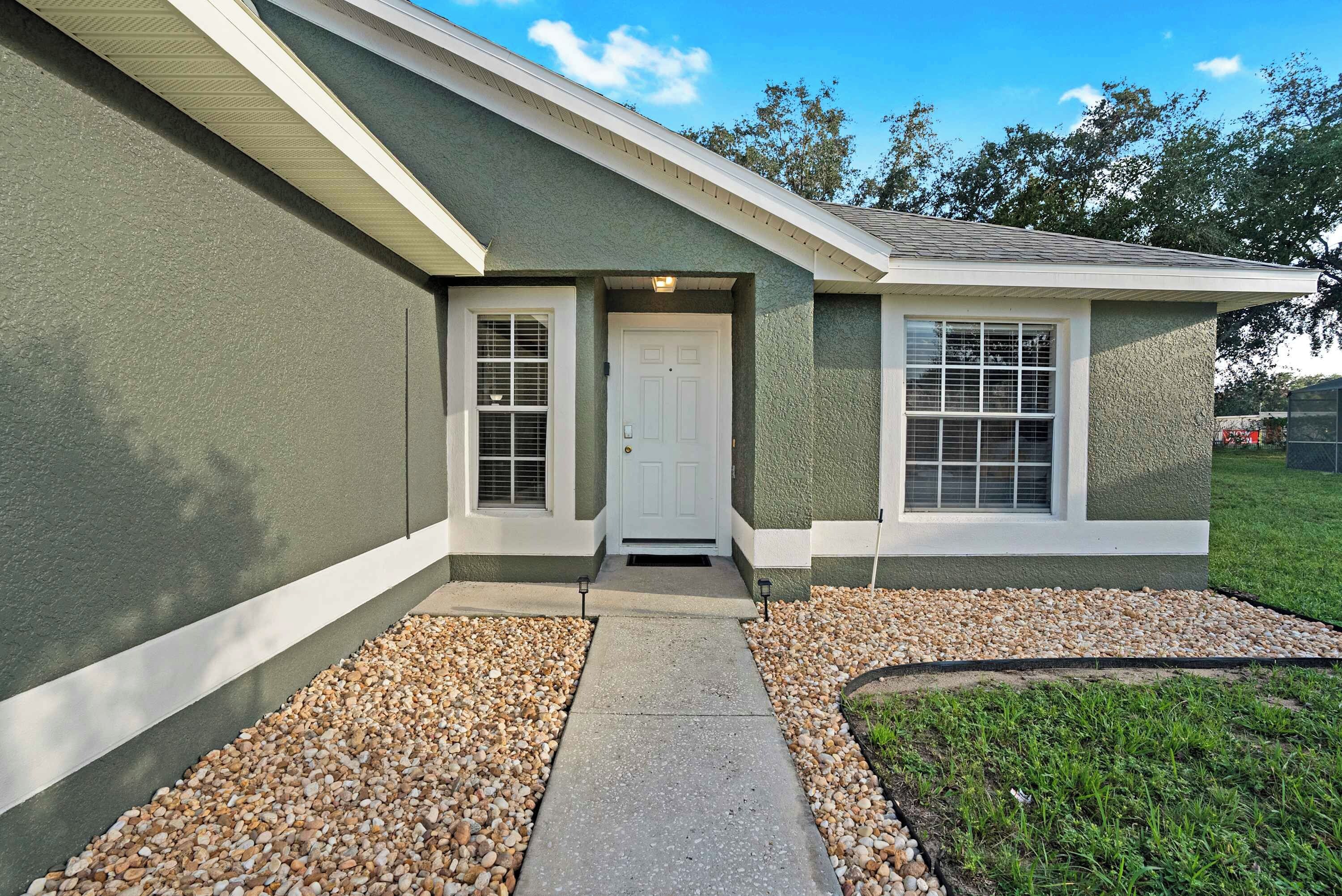 A residential house with a front entrance, two windows with shutters, a door, and a pathway leading to the entrance.