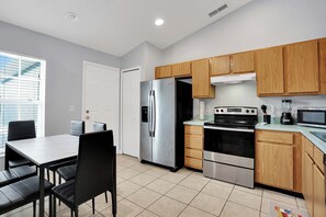 Una cocina moderna con armarios de madera, electrodomésticos de acero inoxidable y un comedor con mesa y sillas.
