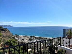 Eine Küstenansicht mit einem Balkon mit Blick auf einen Strand und den Ozean.
