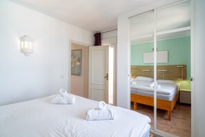 Ein Hotelzimmer mit zwei Betten, einer Schiebetür, einem Bild an der Wand und einer Lampe.