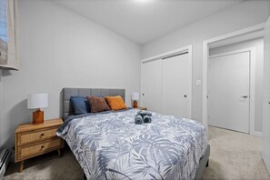 A bedroom with a bed, nightstands, a dresser, and two doors. - Upscale 2BR/2BA Apt | Mins to NAIT, MacEwan & DT - Apartment (Edmonton)