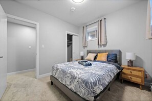 A bedroom with a bed, bedside tables, a wardrobe, and a window with curtains. - Upscale 2BR/2BA Apt | Mins to NAIT, MacEwan & DT - Apartment (Edmonton)