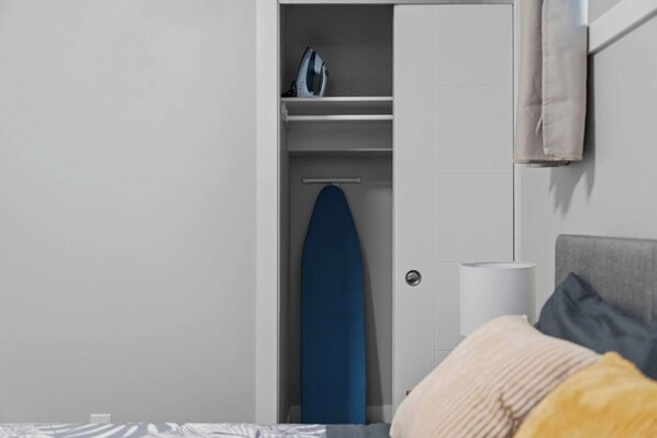 Une chambre à coucher avec un lit, une armoire et une planche à repasser.
