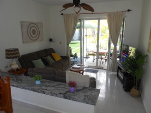 Ein Wohnzimmer mit einer Couch, einem Fernseher und einem Essbereich mit Stühlen und einem Tisch.