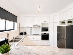 A modern kitchen with white cabinets, stainless steel appliances, and a marble countertop. - **Between Two Blues – Beachfront Bliss in Yeppoon** (Yeppoon)