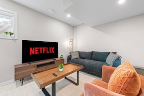 Ein modernes Wohnzimmer mit einem Flachbildfernseher, einer Couch, einem Couchtisch und einer Fernbedienung.