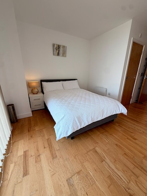 A bedroom with a bed, bedside tables, a lamp, and a door. - Luxurious Mailbox Penthouse 3 Bedrooms 3 Bathrooms (Birmingham)