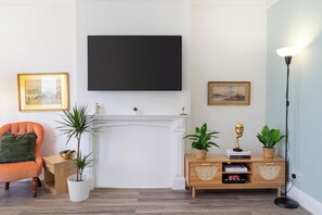 Ein Wohnzimmer mit Kamin, einem an der Wand befestigten Fernseher und einem Bücherregal mit Dekorationselementen.