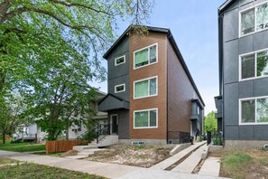 A modern multi-story residential building with a brick facade, large windows, and a visible staircase leading to the entrance. - Stylish 1BR Guest Suite | Near UofA, Whyte & DT - Double Room (Edmonton)
