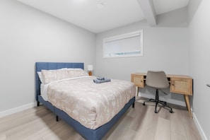A bedroom with a bed, a desk, and a chair.