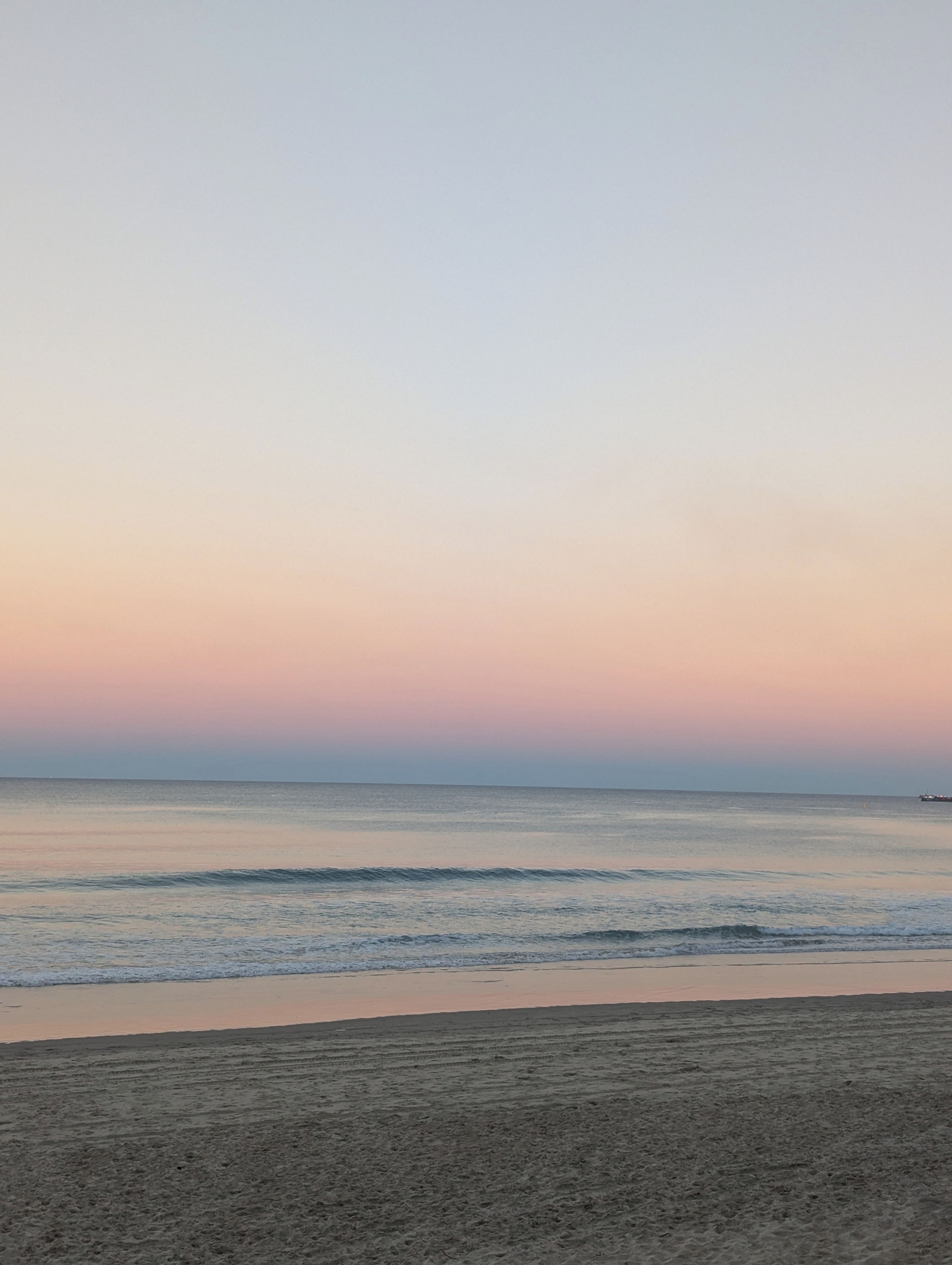 A beach with a calm sea and a clear sky.