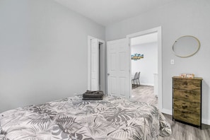 Ein Schlafzimmer mit Bett, Kommode und einer Tür zu einem anderen Raum.