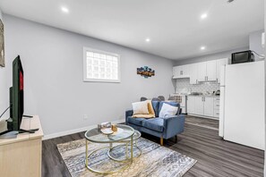 A modern living room with a sofa, coffee table, and a television. - Chic Getaway | 1BR Suite w/ Parking & AC (Windsor)
